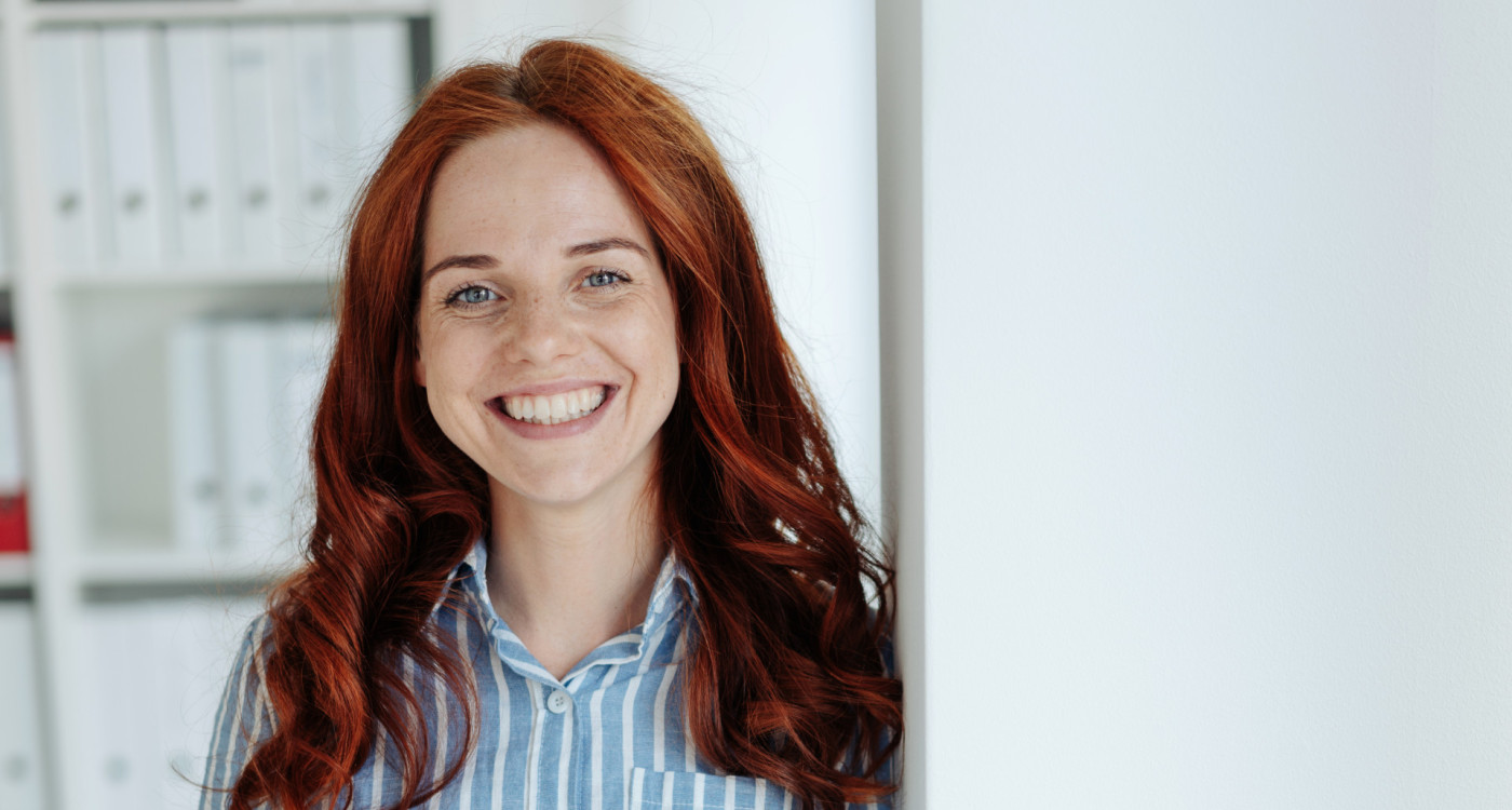 Dame stehend, lächelt in die Kamera.