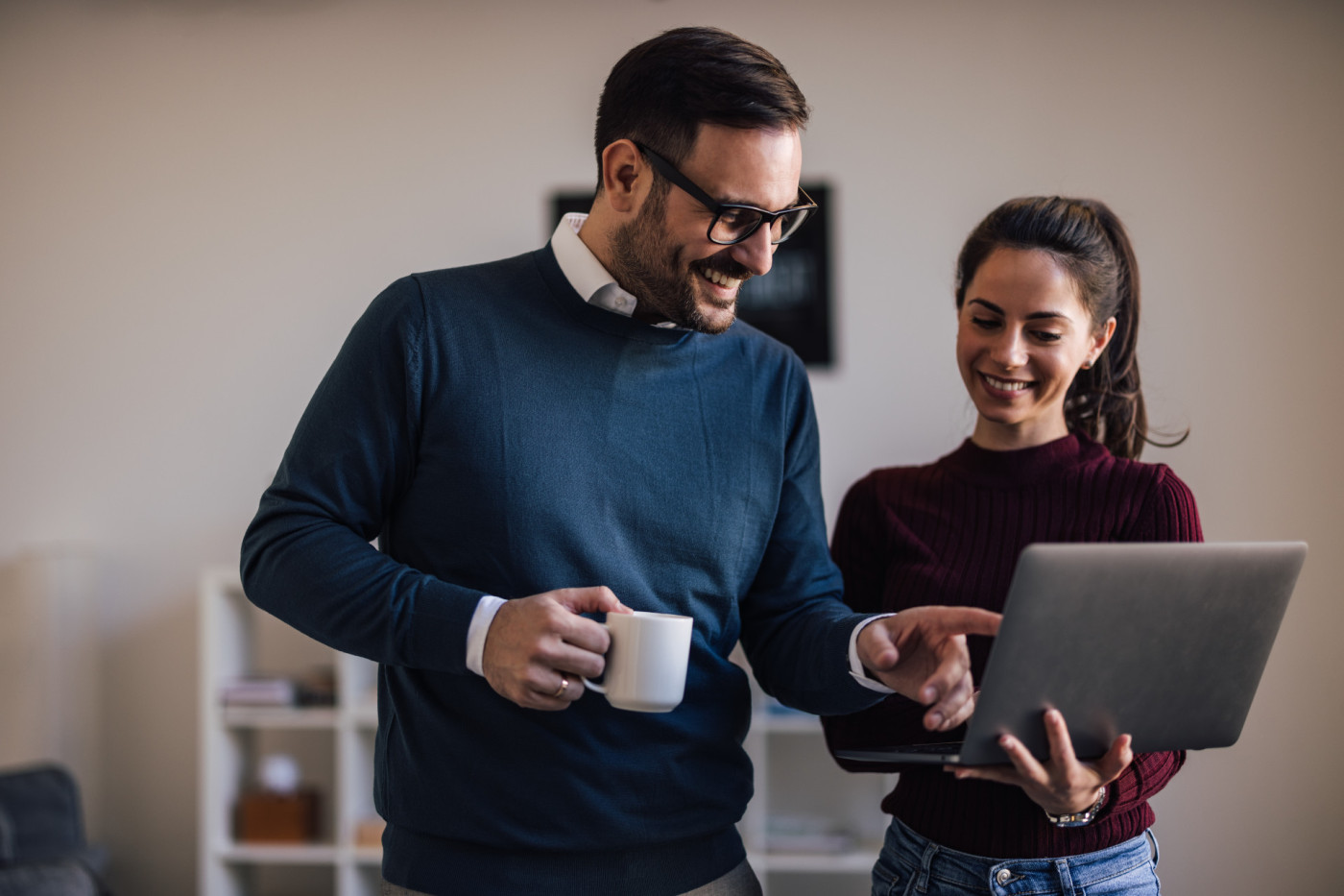 Lächelnde Kollegen, verbringen gemeinsam eine Kaffeepause und schauen in den Laptop
