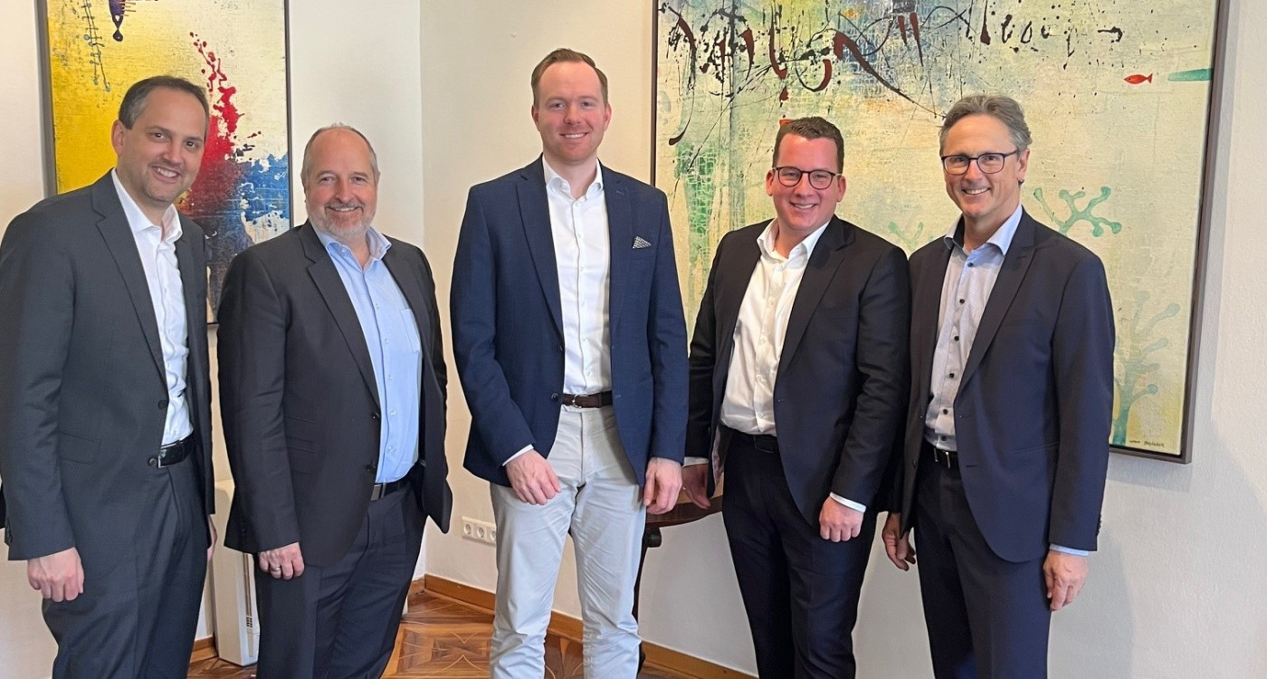 Fünf Partner stehen nebeneinander im Notariat und blicken in die Kamera